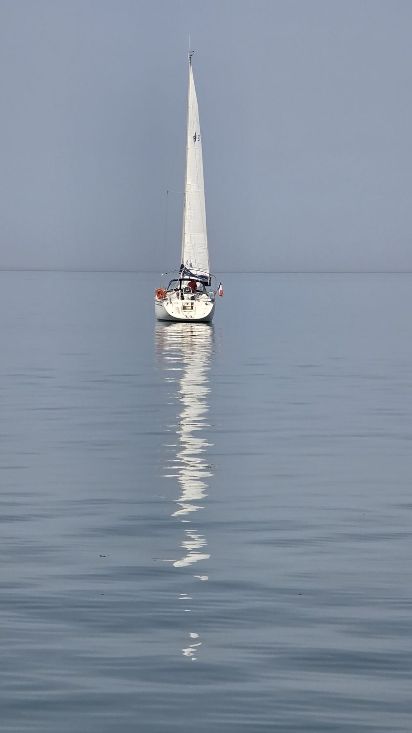 Voilier se reflétant sur une mer d'huile, lumière calme